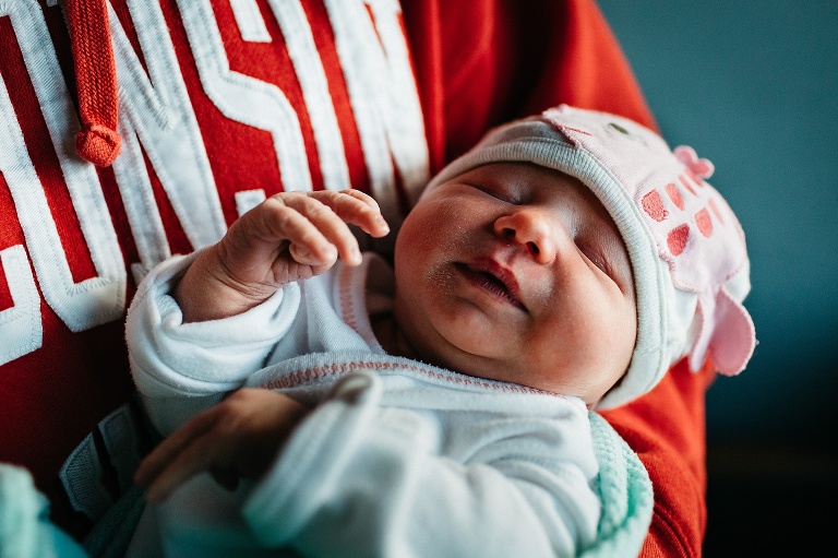 Father holds sleeping newborn baby in his arms.