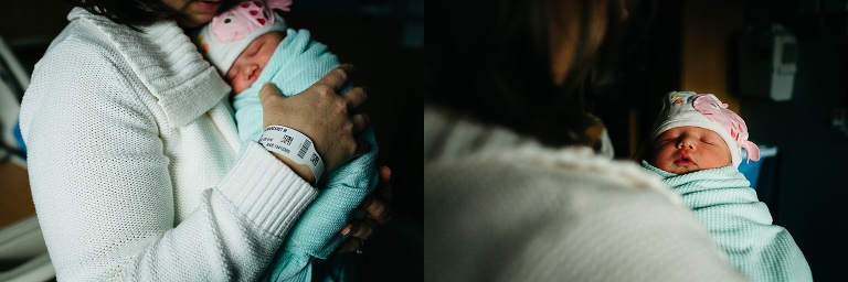 Mother holds swaddled newborn baby girl in the hospital.