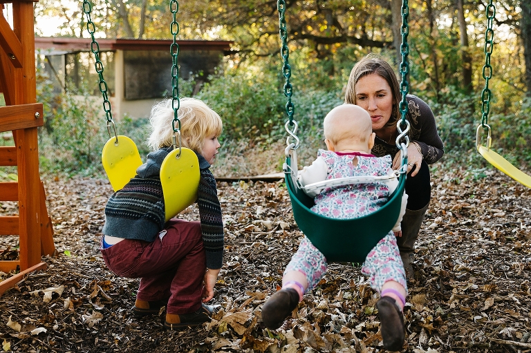 Mom engages with two young children on swings. 