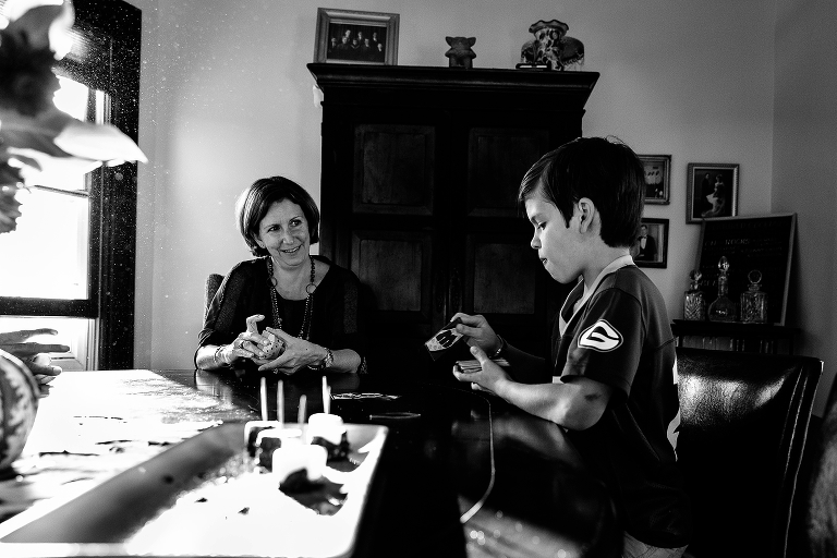 Mom plays card game with young son at dining room table. Black and white. 