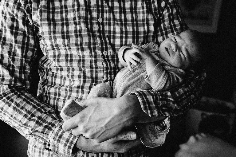 Black and white. Father holds newborn baby.