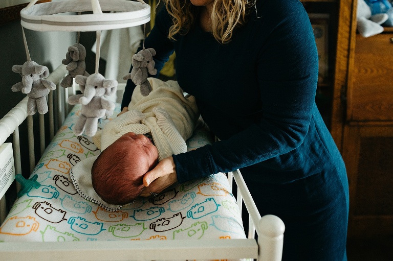 Mother lays newborn baby down onto changing table.