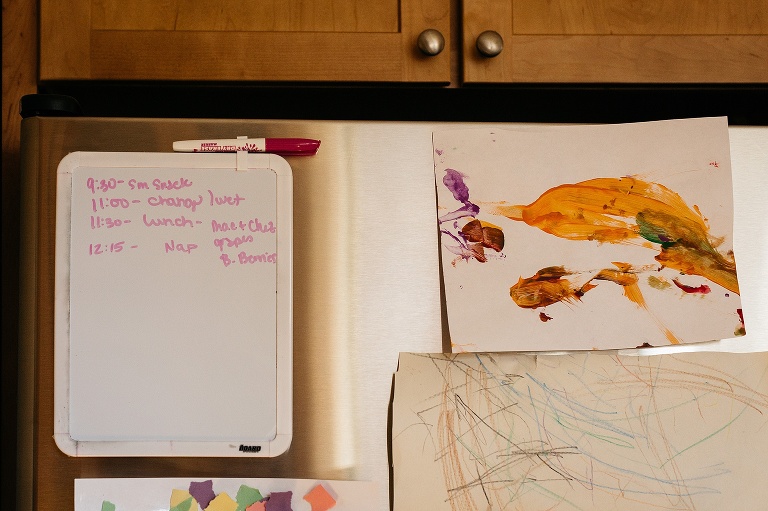 Kitchen fridge with children's art work and whiteboard schedule.