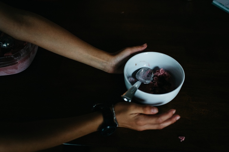 Hands holding onto bowl of homemade strawberry ice cream.