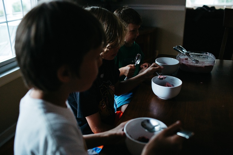 Three boys sit at kitchen table eating homemade strawberry ice cream.