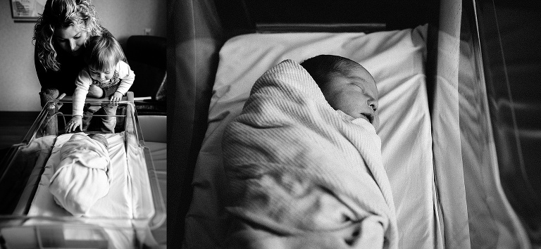 Black and white. Mother holds son up to newborn baby sleeping in hospital crib.