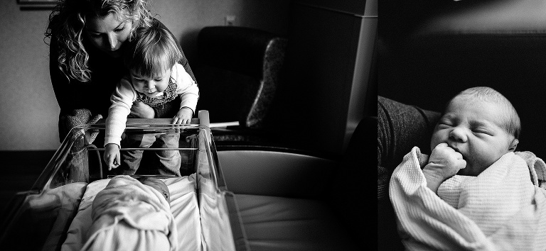 Black and white. Mother holds son up to newborn baby sleeping in hospital crib.