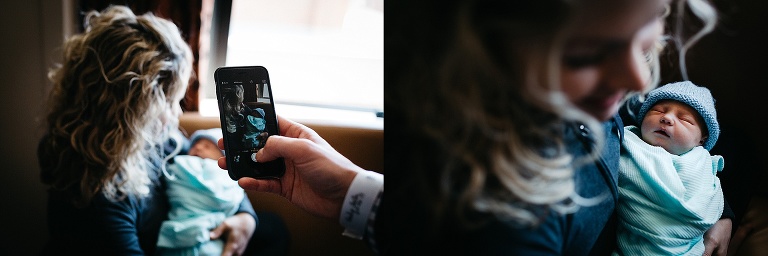 Father photographs mother holding sleeping newborn baby.