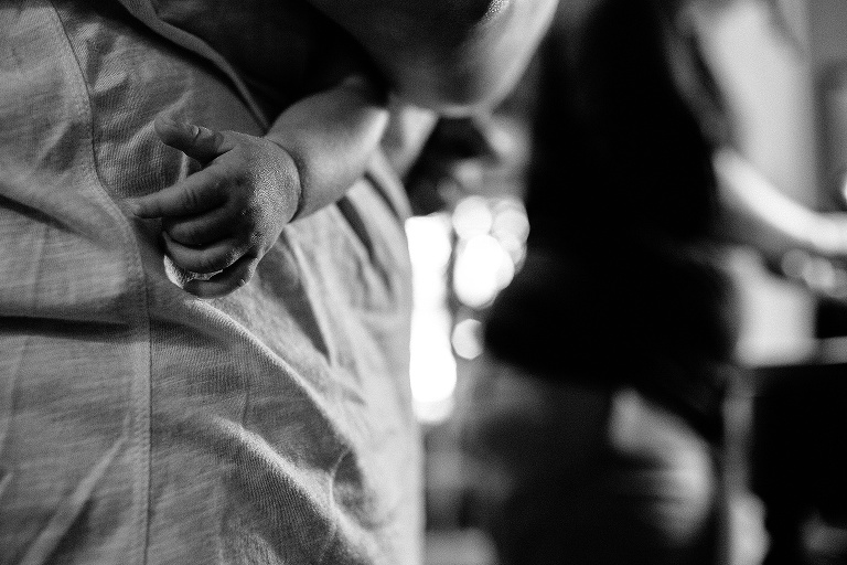 Black and white. Baby's tiny hand resting on mothers shirt.