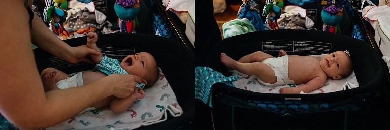 Baby boy laying on changing table as his mother puts a blue onesie on him.