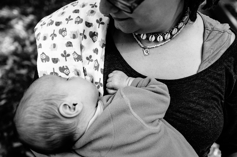 Black and white. Mother holding sleeping baby boy. mother has burp cloth hung over her shoulder.
