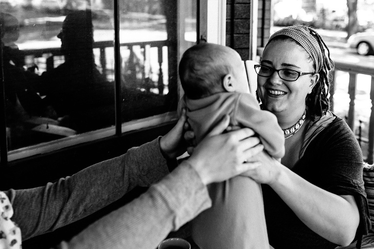 Black and white. Mother picks up baby son while sitting on porch patio.