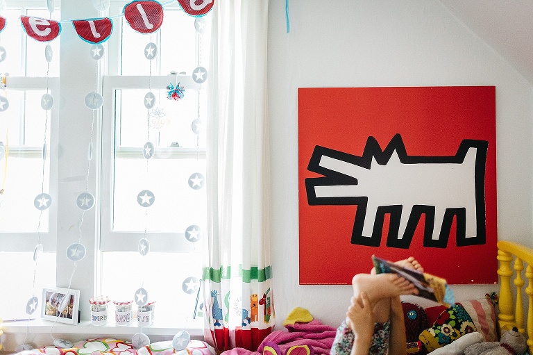 Young girl reads a book in her colorful bedroom.