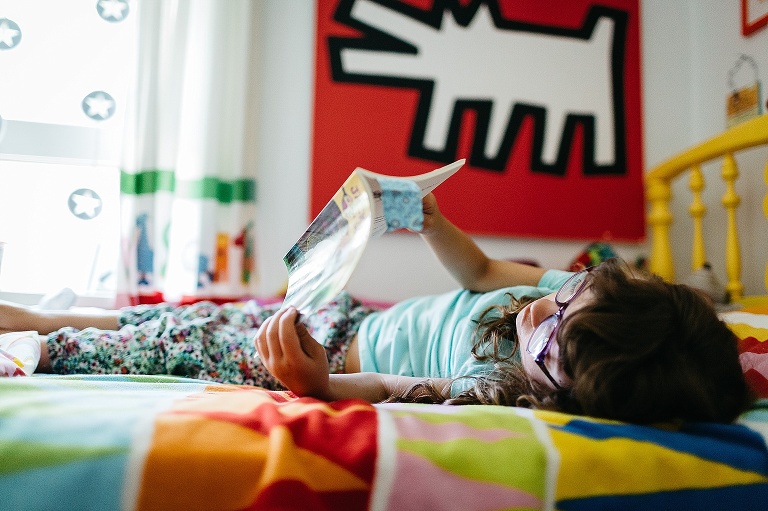 Young girl reading in her colorful bedroom.