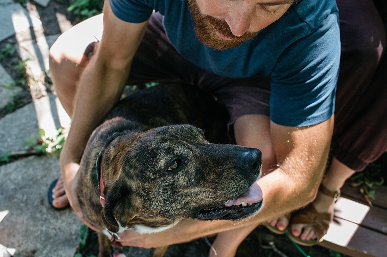 Father sits petting his dog.