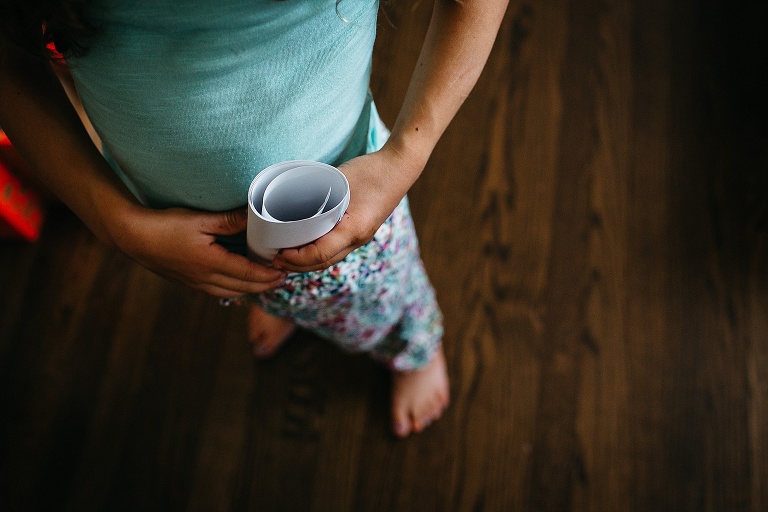 Young girl puts a treasure map rolled up in her pants waistband.