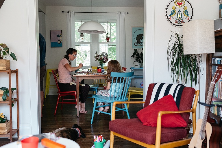 Mother and daughter sit a kitchen table eating breakfast.