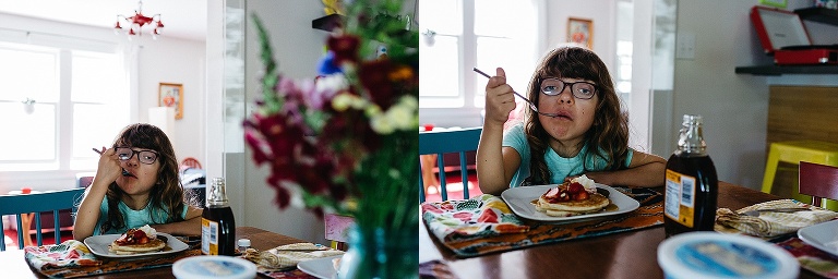 Young girl eats fresh strawberry pancakes.