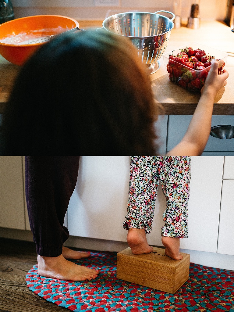 Young girl pours a cartoon of strawberries into a colander.