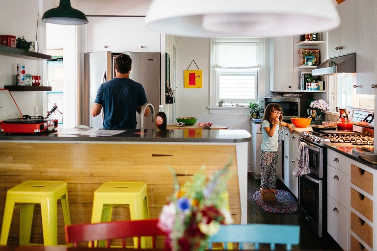 Father and daughter cook pancakes in a colorful kitchen.