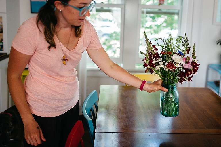 Woman sets a fresh bouquet of flowers on a kitchen table.