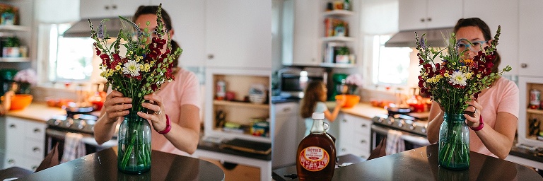 Woman arranges a bouquet of flowers in a mason jar vase in the kitchen.