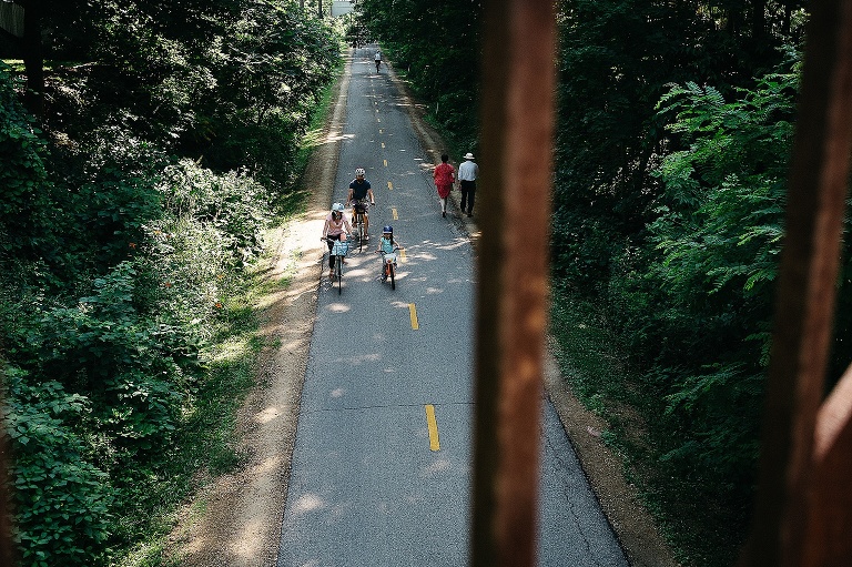 Mom, dad, and daughter bike on a bike path on their way home from a farmers market.