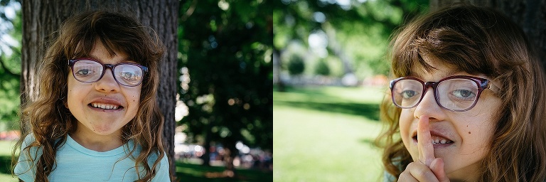 Young girl hides behind a tree pointing her finger to her mouth to be silent while playing a game of hide and seek at a park.