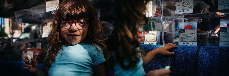Young girl holds blue cookie with blue frosting all over her mouth.