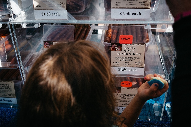 Young girl stands and looks at a counter of beef jerky.