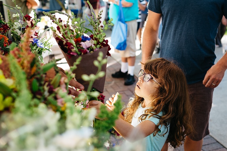 Young girl at a farmers market buys a bouquet of flowers.