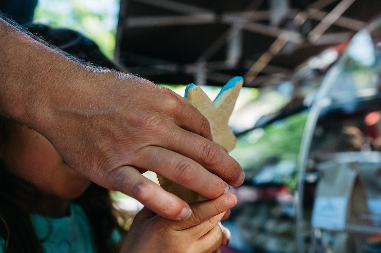 Fathers hand giving a blue star cookie to his daughter.