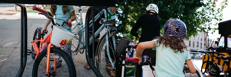 Young girl parks her bike at a bike rack next to her mothers bike.