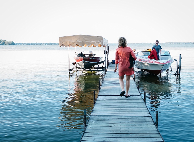 Mother walks down a dock on a lake to her boat.