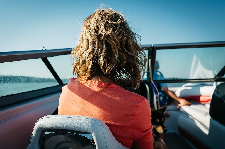 Mothers wind blown hair as she sits on a boat.