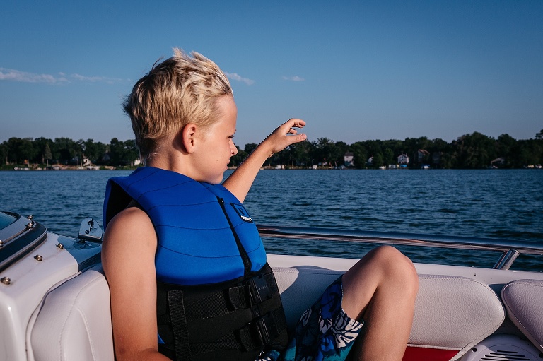 Boy wearing a life jacket sitting in the front of a motor boat.