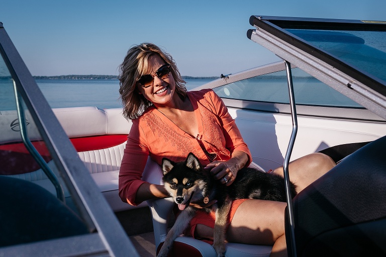 Mom sitting on a boat holding a puppy on her lap.