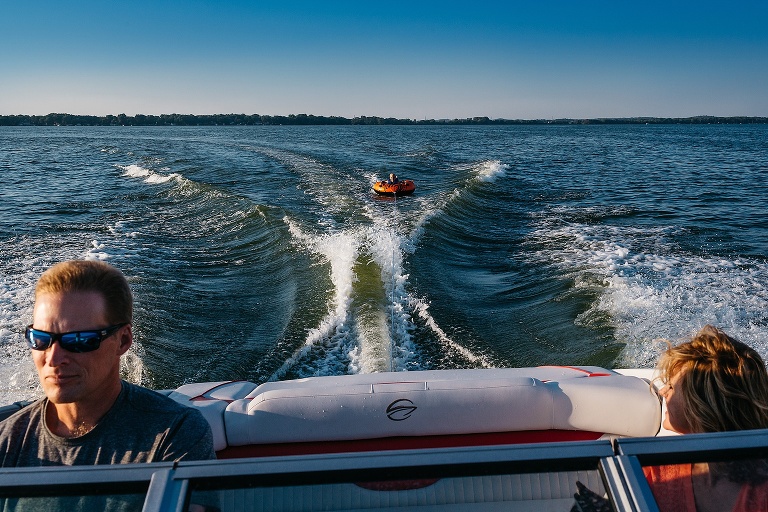 Parents on a motorboat kid tubing behind them.