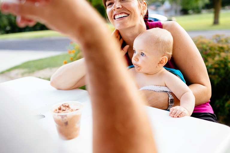 Mom smiles holding onto son as dad eats chocolate ice cream.