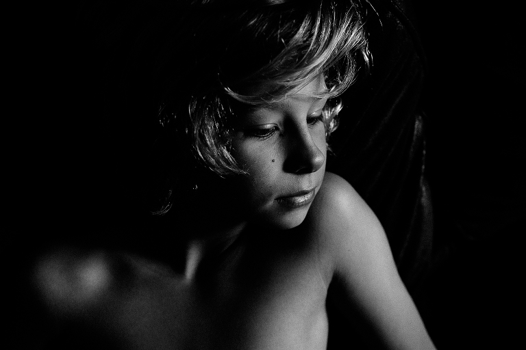 Black and white. Closeup on boys face shadows on his body.