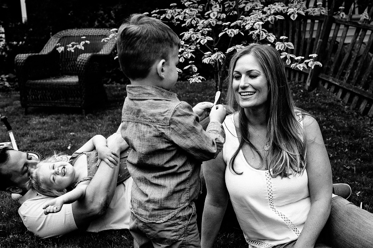 Black and white. Mother, father, son, and daughter play in backyard.
