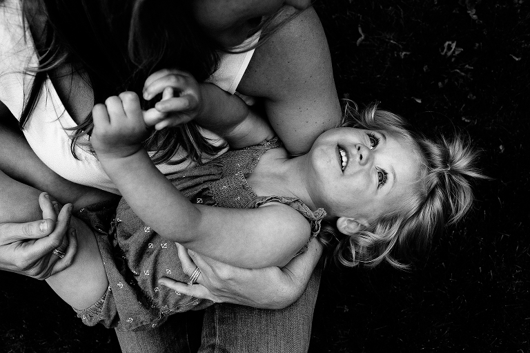 Black and white. Mother cradles daughter in her arms as she looks into her mothers eyes.