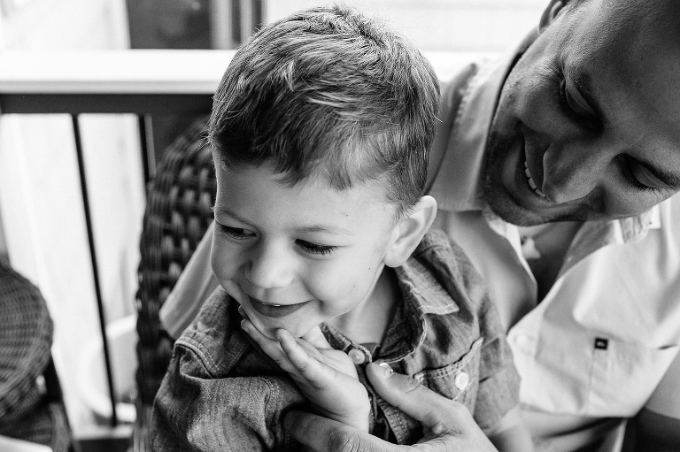 Black and white. Young boys sits outside on fathers lap.