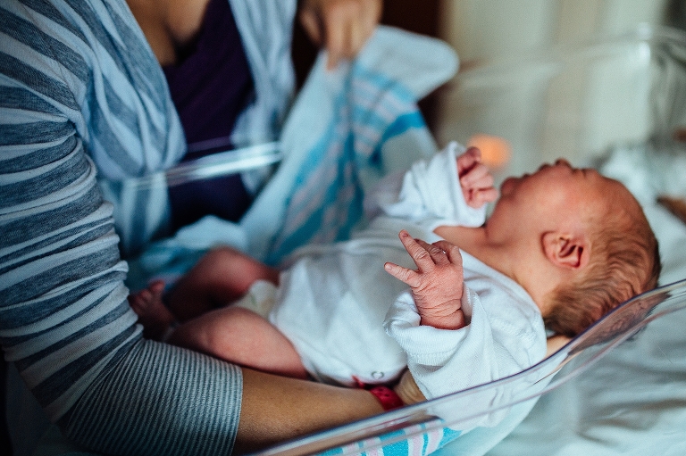 mom picks up newborn in a hospital bed