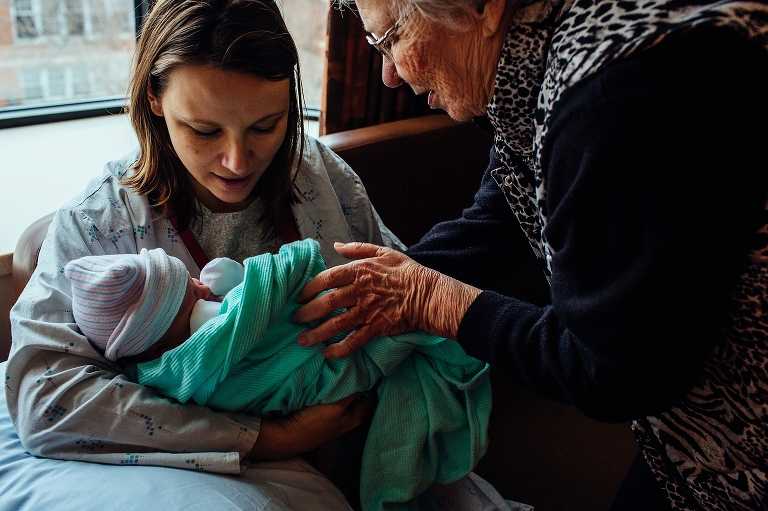 Great-grandmother gives granddaughter her newborn baby to hold in a hospital