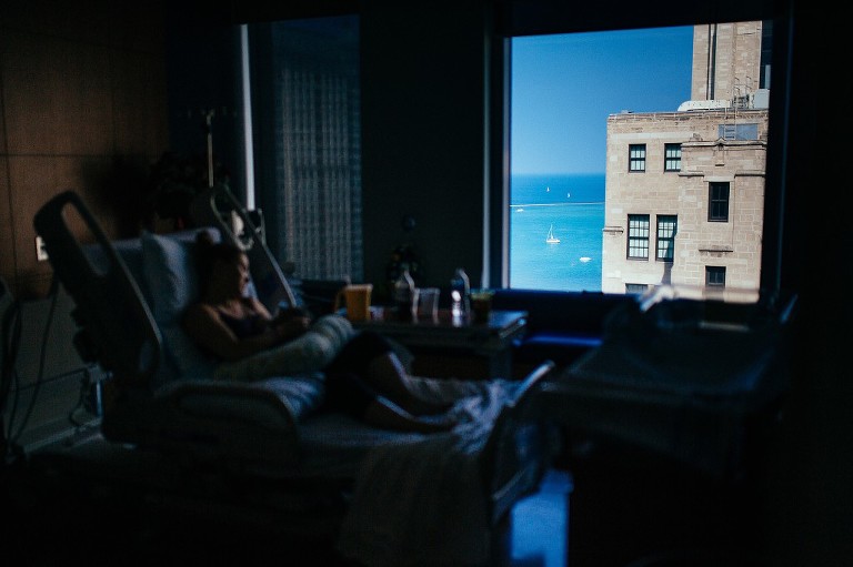 Mother nurses newborn in a hospital bed over looking sailboats in Lake Michigan 