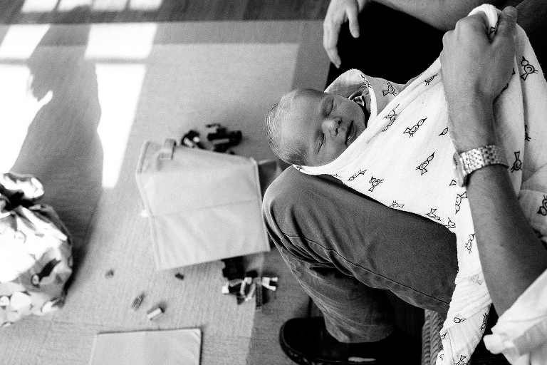 Black and white. Father swaddles newborn baby in bird baby blanket.