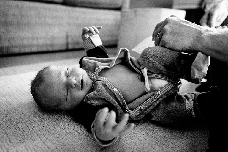 Black and white. Newborn baby sleeps on floor while getting clothes changed