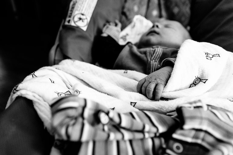Black and white. Newborn baby sleeps in carseat with blankets on him