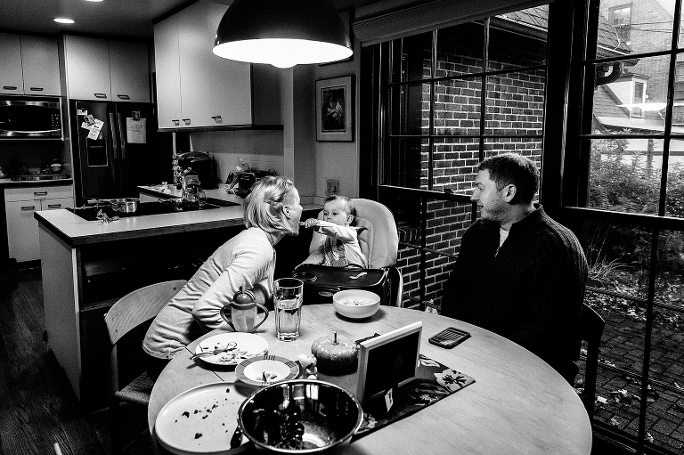 Black and white, Family sits down for dinner. baby in highchair feed mom some of her dinner